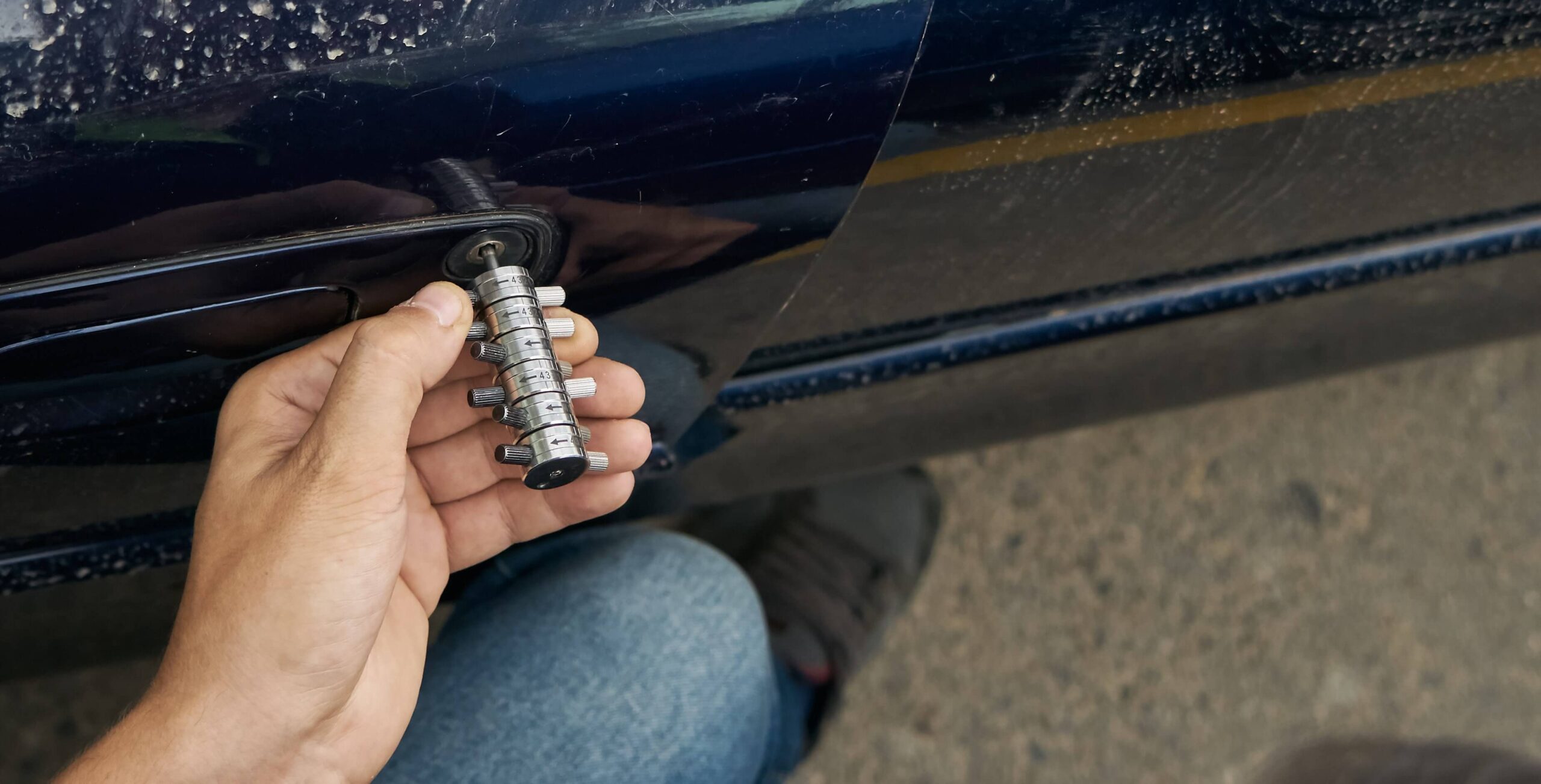 Locksmith performing a car lockout service using a tool to open a car door.